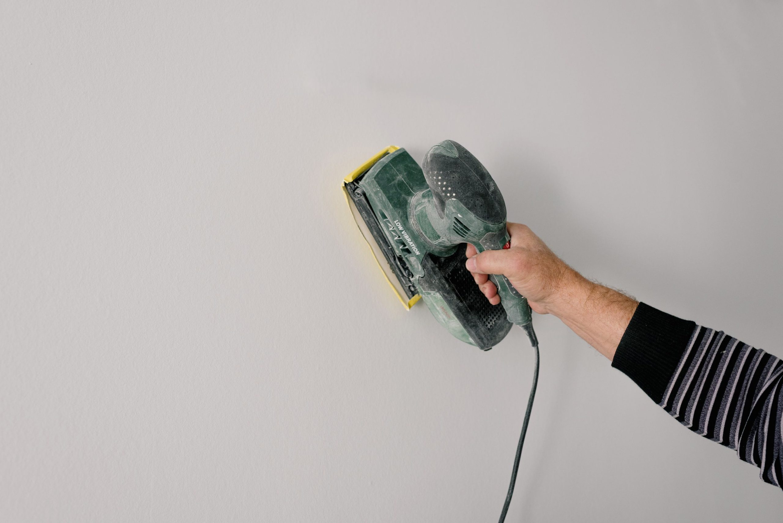 Ouvrier poncant un mur en renovation