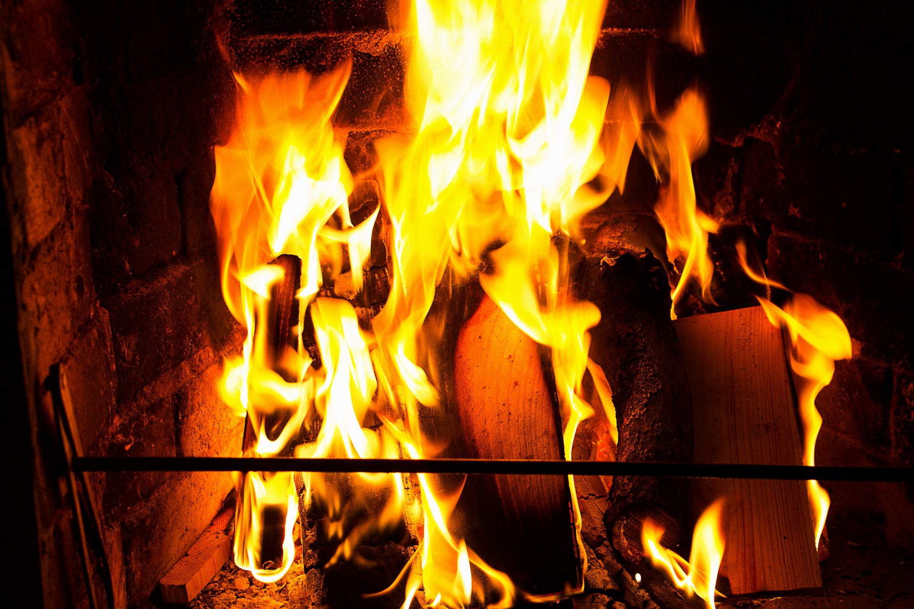 Flammes vives sur des bûches dans un foyer en brique