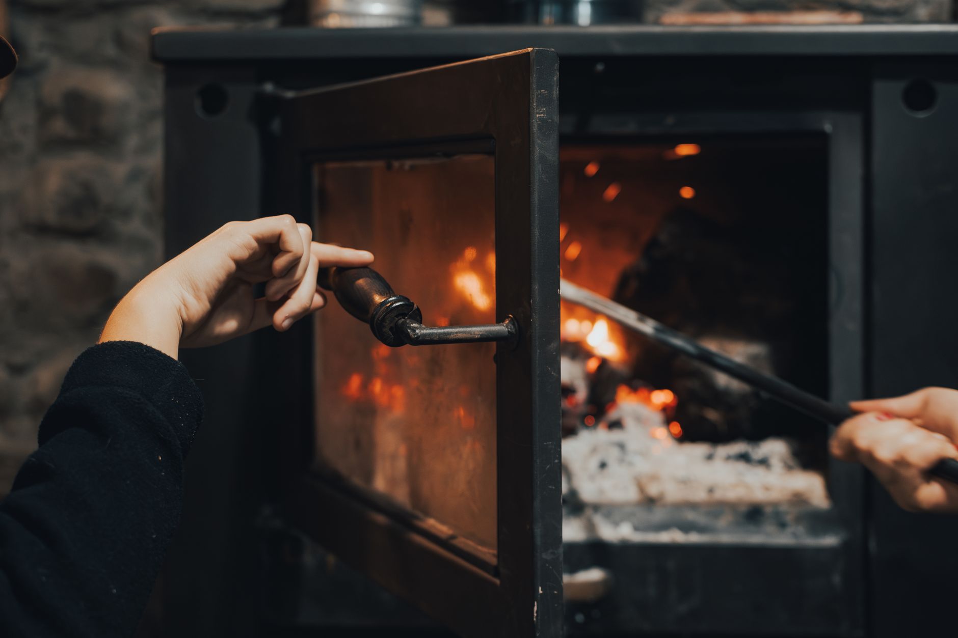 Mains qui entretiennent un feu dans un poêle