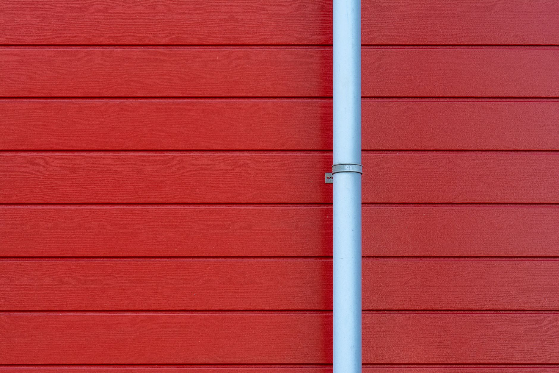 Gouttière blanche fixée sur un mur rouge